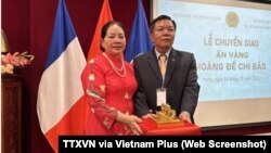 Chủ tịch Hội Cổ vật Bắc Ninh Nguyễn Thế Hồng (phải) đứng cạnh ấn vàng Hoàng đế chi bảo tại lễ chuyển giao cổ vật này tại Đại sứ quán Việt Nam ở Pháp, hôm 16/11. Ông Hồng mua chiến ấn triện vàng đúc từ thời vua Minh Mạng với giá 6,1 triệu euro.