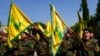 Konbatan Hezbollah yo flote drapo epi kriye slogan pandan fineray yon solda Hezbollah ki rele Bilbl Nemr Rmeiti ki mouri nan yon atak Izrayelyen nan sid Liban, 22 Oktob, 2023. 