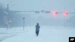 Một người dân đi trên tuyết trong cơn bão mùa đông ở Grand Prairie, Texas. 