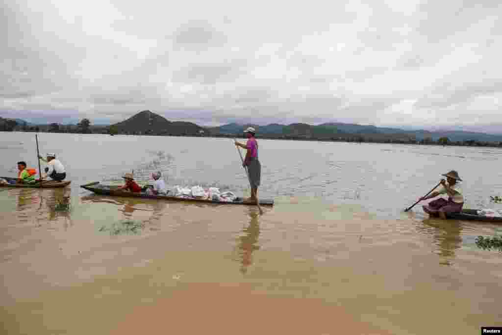 Residents transport aid on boats for their flooded village at Kawlin township, Sagaing division, Myanmar July 23, 2015. Heavy rains caused flooding over 20,000 acres of rice field and in about a hundred villages, killing at least eight people, according t