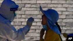 A resident gets her throat swabbed during a mass COVID test, in Beijing, May 16, 2022.