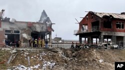 Emergency workers clear up debris after an airstrike hit a tire shop in the western city of Lviv, Ukraine, Monday April 18, 2022.