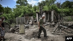 A man walks through the yard of a damaged house after shelling in which two people were killed in the city of Lysychansk in the eastern Ukrainian region of Donbas on June 13, 2022.