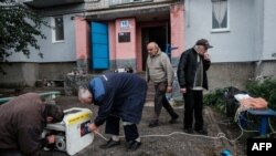 Residents use a generator to charge their mobile phones and flashlights in front of their apartment building in Kupiansk, Kharkiv region, Sept. 24, 2022, amid Russia's military invasion on Ukraine.