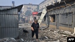 A woman passes by destroyed shops on a local market after a rocket attack in the Ukrainian town of Sloviansk, on July 3, 2022, amid the Russian invasion of Ukraine. 