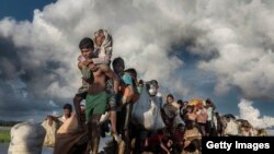 Rohingya refugees fleeing Myanmar cross a muddy rice field in Palang Khali, Bangladesh, in October 2017. (IWMF/Paula Bronstein)