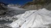 A man works at the Rhone Glacier partially covered with insulating foam to prevent it from melting due to global warming near Gletsch, Switzerland, Oct. 27, 2021. 