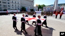 Мужчины несут национальный флаг Грузии во время празднования Дня независимости Грузии в Тбилиси, Грузия, 26 мая 2022 года.