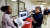 FILE - Renee Phifer, Rockdale County board of elections assistant director, left, demonstrates a new voting machine at a polling site to Kelly Monroe, investigator with the Georgia secretary of state office in Conyers, Ga. 