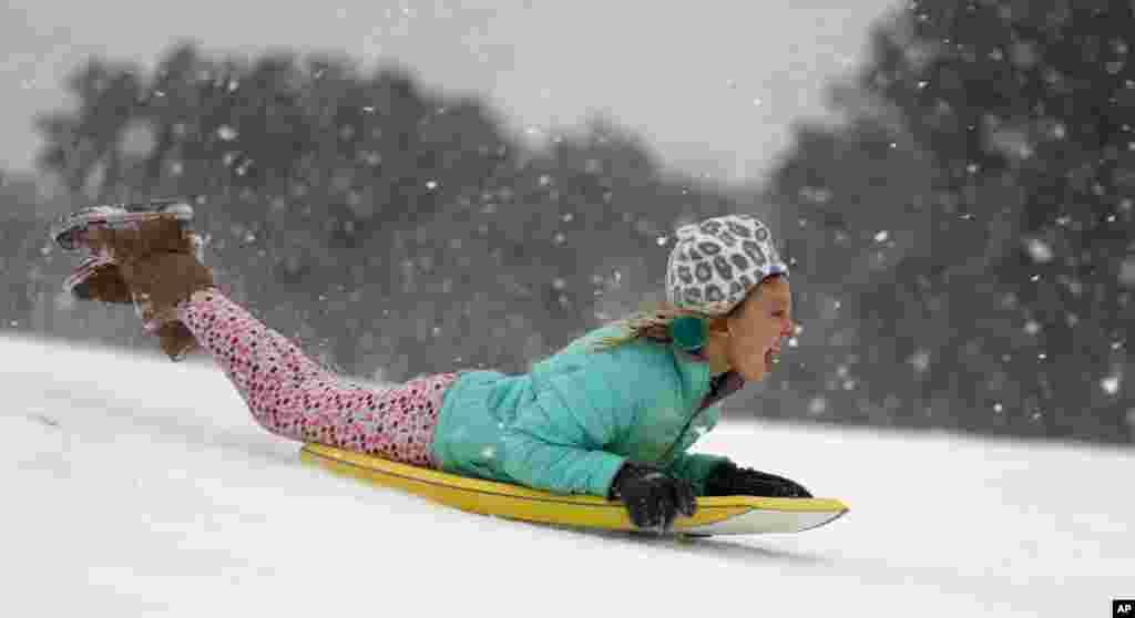 Finley Bork, 7, uses a boogie board, typically used on the beach, for sledding down a hill on a golf course at the Isle of Palms, South Carolina.