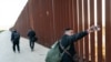 Migrants camp at the border wall on the U.S. side