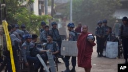 Buddhist monks walk expecting alms as group of policemen(AP Photo/Gemunu Amarasinghe)