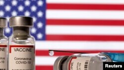 FILE PHOTO: Illustration shows vials labelled "VACCINE Coronavirus COVID-19" and a syringe in front of a displayed U.S. flag