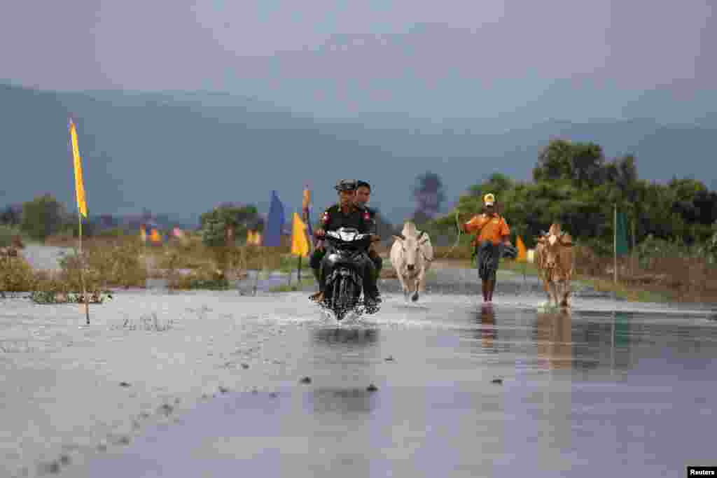 Soldiers ride a motorbike on a flooded road at Kawlin township, Sagaing division, Myanmar