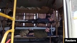 Service members of Ukrainian forces who left the besieged Azovstal steel plant are seen inside a bus in Mariupol