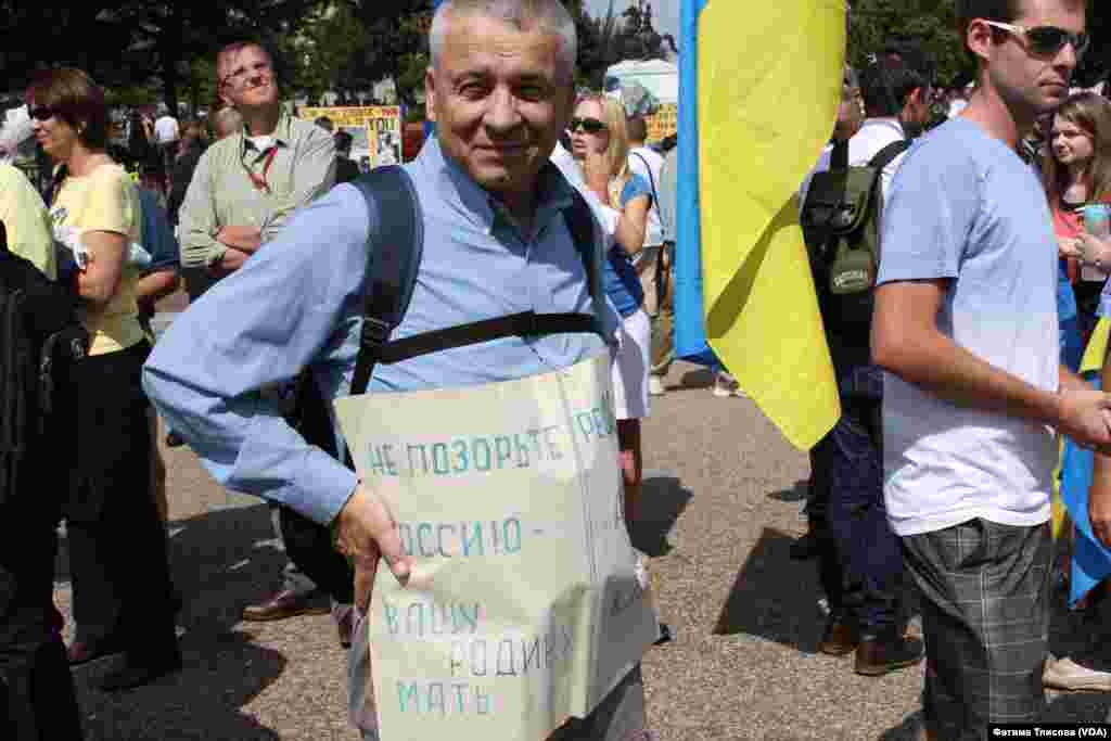 На прикрепленном к сорочке большими канцелярскими скрепками самодельном плакате призыв к россиянам - очень хочется, чтобы нас услышали и увидели люди в России, говорит этот человек 