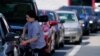 A customer pumps gas at Costco, as others wait in line, in Charlotte, N.C., May 11, 2021.