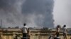 Black smoke billows from the industrial zone of Hlaing Thar Yar township in Yangon, Myanmar Sunday, March 14, 2021. Attacks on Chinese-run factories in Myanmar's biggest city drew demands Monday from Beijing for protection for their property and employees, while many in Myanmar e