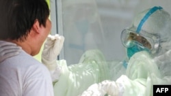 A medical officer (R) takes a swab sample from a man to be tested for the COVID-19 coronavirus at a quarantine centre in Yangon on May 16, 2020. (Photo by Ye Aung THU / AFP)