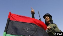 Yon rebèl k ap fè jès kot drapo libyen an sou tèt yon machin nan lès Brega 4 avril 2011