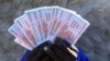 A man holds a handful of 5 Billion Zimbabwean dollar notes, in Harare.