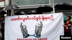 Journalists hold a banner as they protest against a law