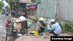 Một tình nguyện viên của nhóm bác ái Fiat trao một phần cơm cho người nghèo ở Tp. Hồ Chí Minh. Photo Vu Thi Kim Huong.