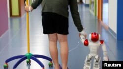 Belgian Ian Frejean, 11, walks with "Zora" the robot, a humanoid robot designed to entertain patients and to support care providers, at AZ Damiaan hospital in Ostend, Belgium June 16, 2016.