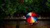 A woman carries a rainbow-colored umbrella as she walks during a rain shower in Beijing.